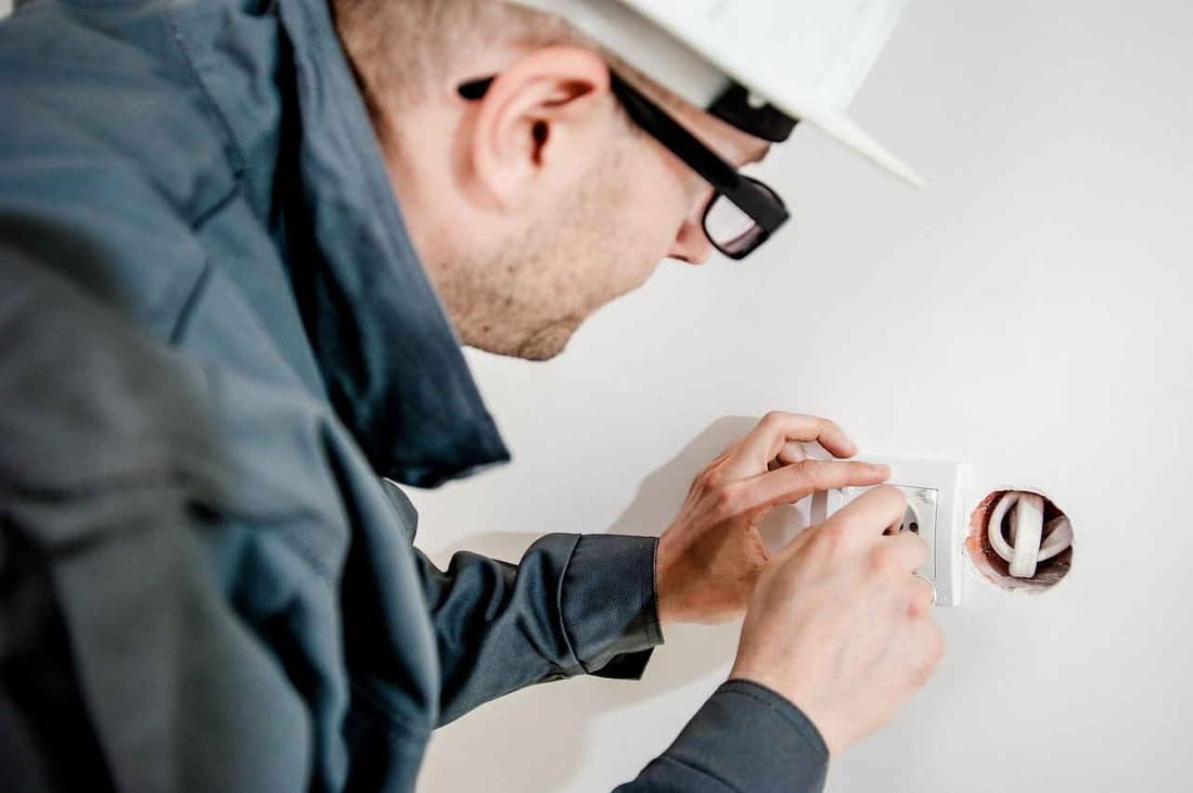 Elektriker montiert eine Steckdose an einer fertig verputzten Wand